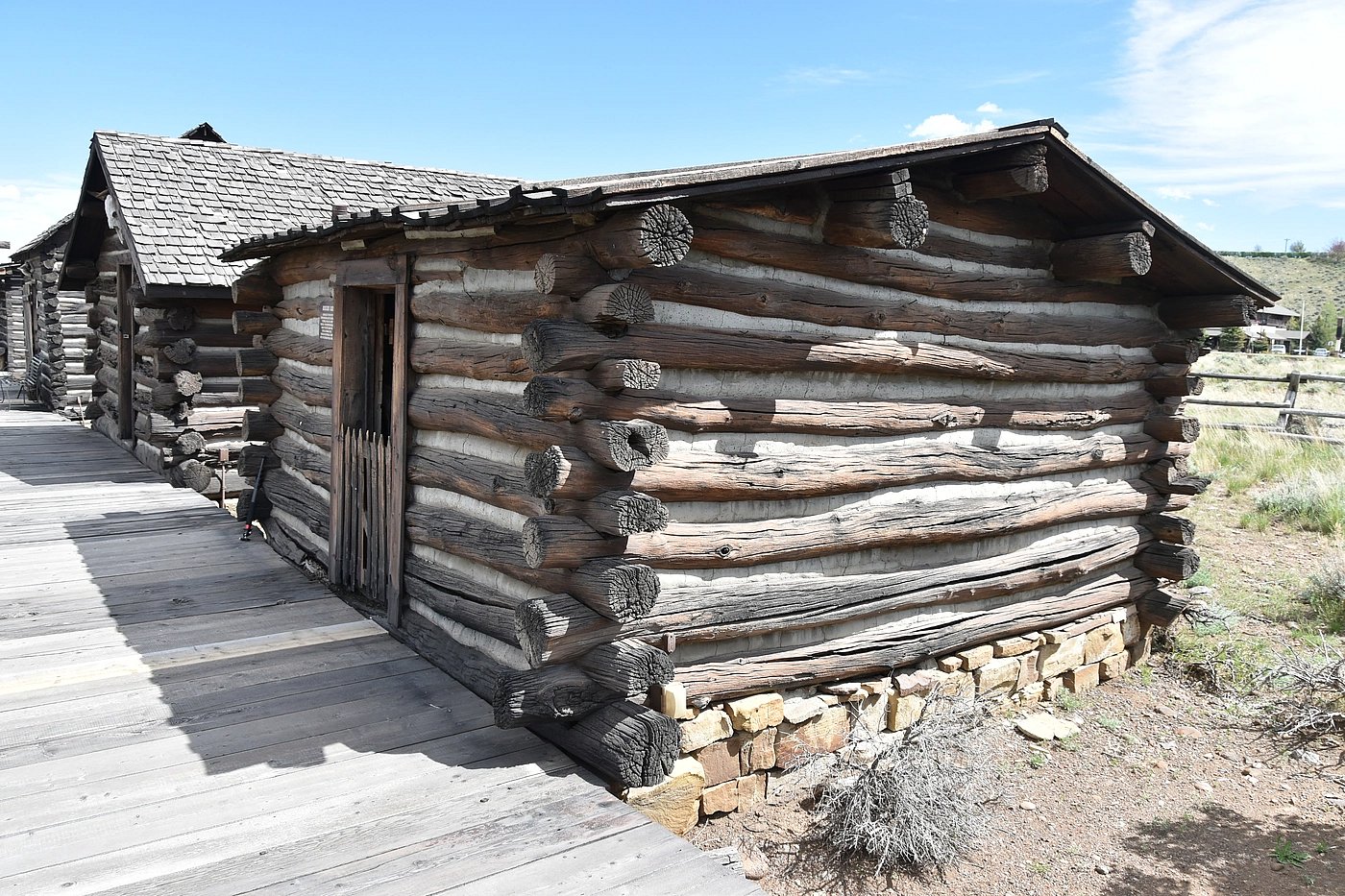 Exterior of Morrison cabin from the side with jagged Wyoming weeds
