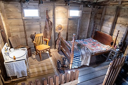 A humble cabin with bed, vanity, and toilet