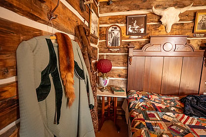 Period specific female clothing featured next to a bed and western photos